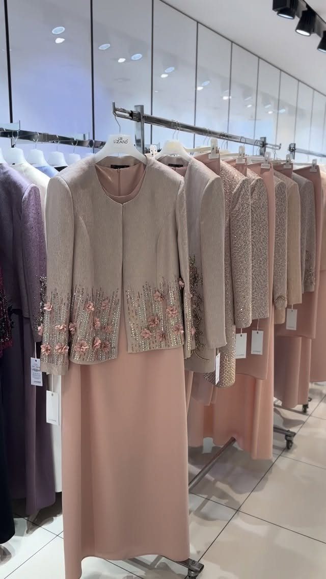 Champagne formal jacket with pink floral embroidery paired with a matching long skirt on a clothing rack.