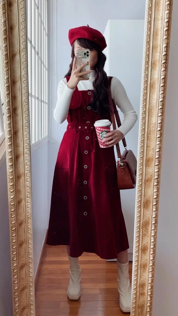 Woman in a red velvet midi dress and cream ankle boots posing in a mirror.