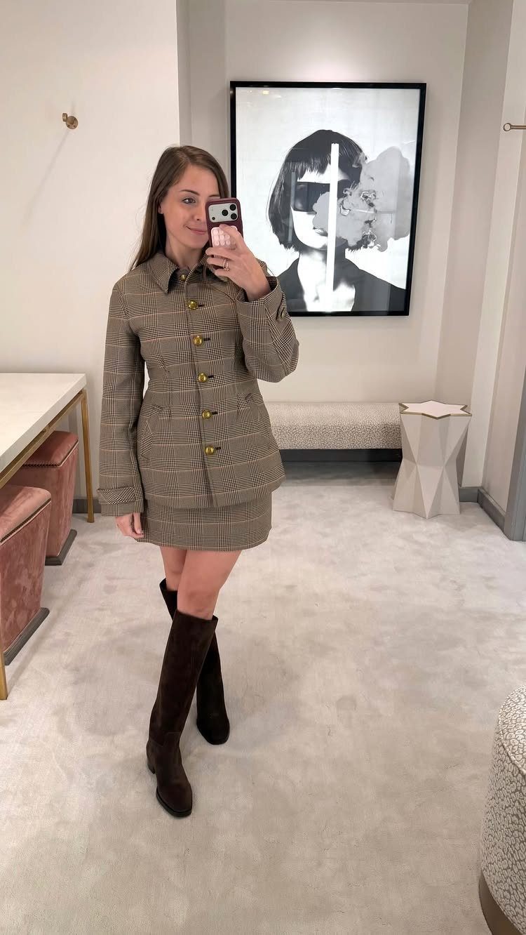 Woman in a brown plaid jacket and skirt set with dark brown knee-high boots.