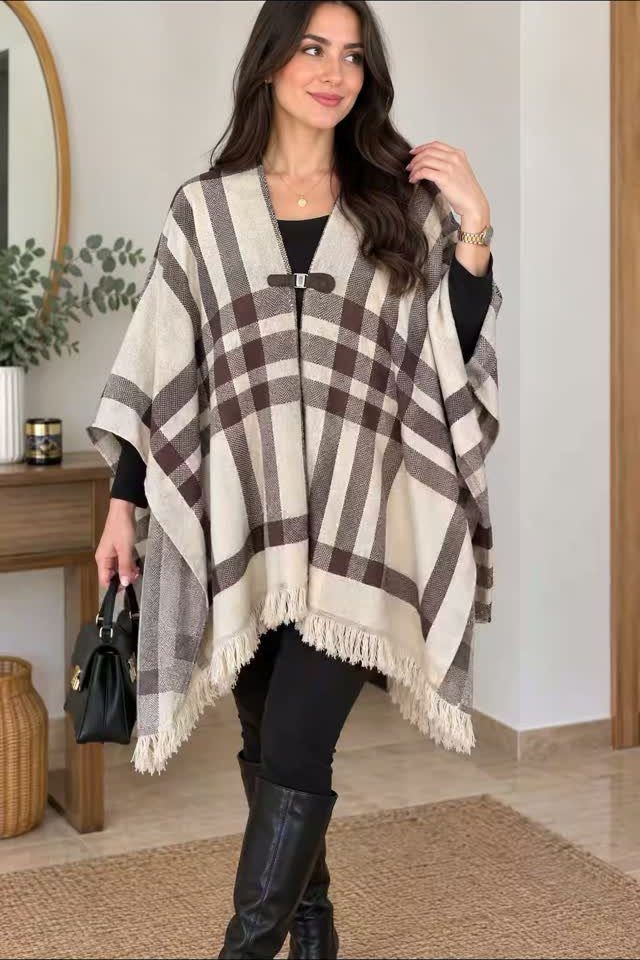 Woman wearing a cream and brown plaid fringe poncho with black leggings and boots.