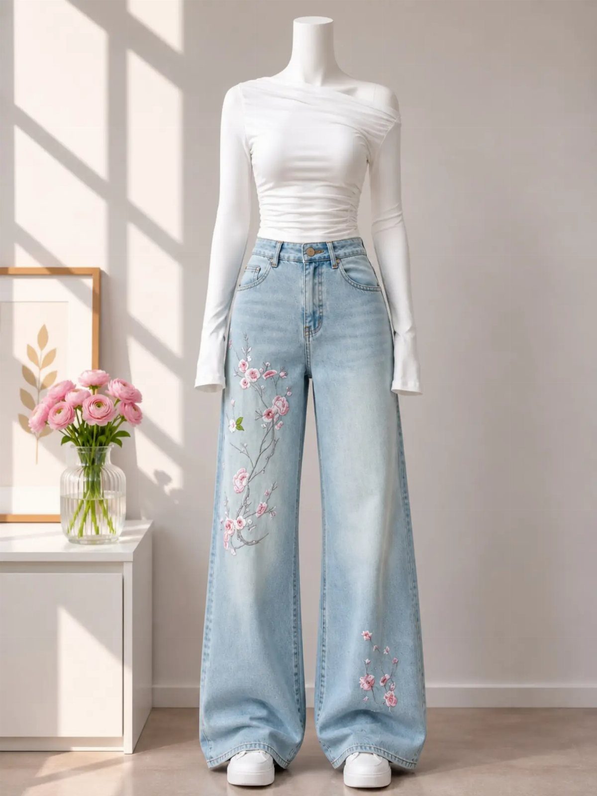 Mannequin wearing white long-sleeve top and light blue wide-leg jeans with pink floral embroidery.