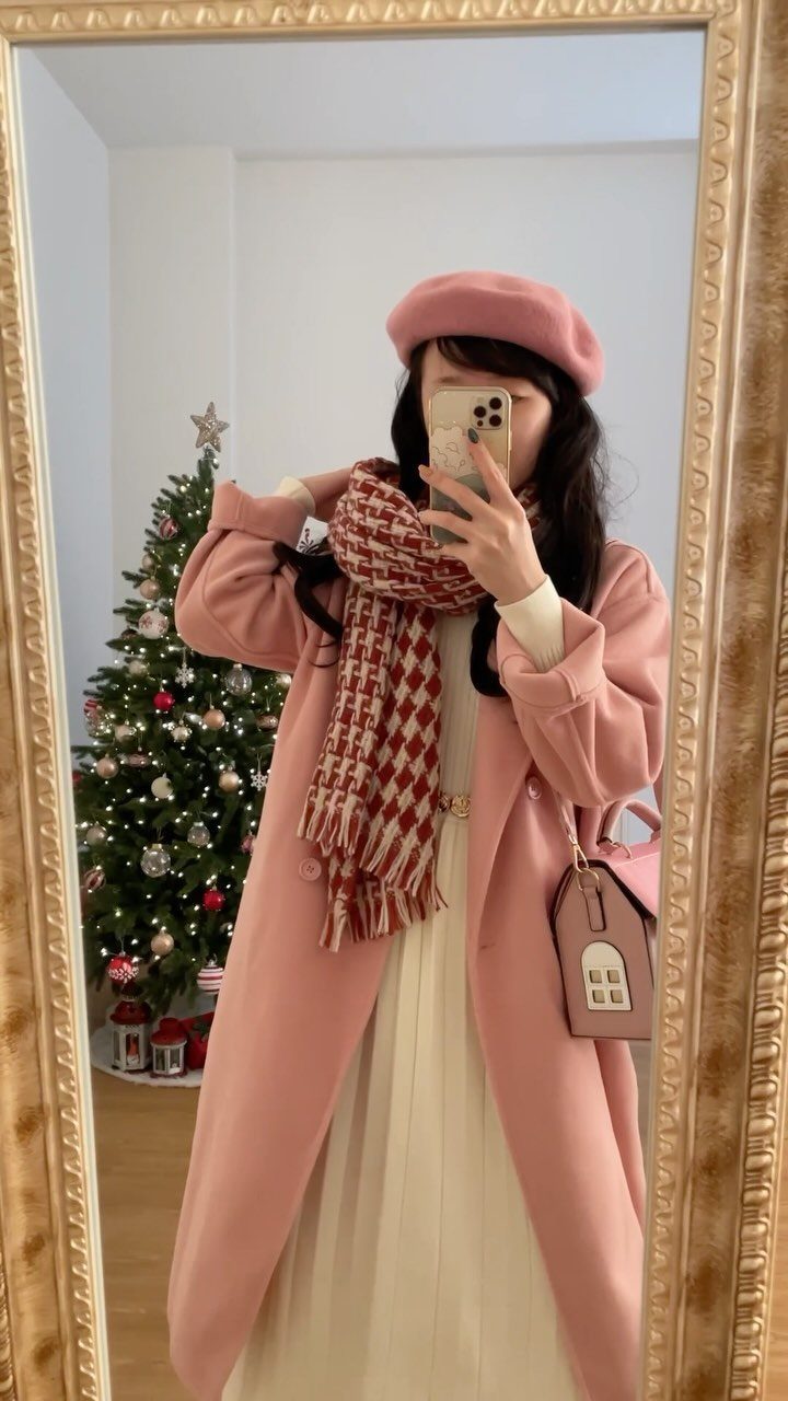Woman in a pink coat and beret wearing a white pleated midi dress.