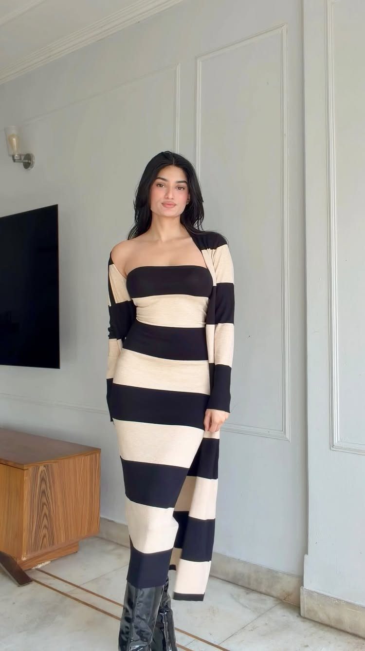 Woman in a striped knit sweater dress and matching cardigan with black leather boots.