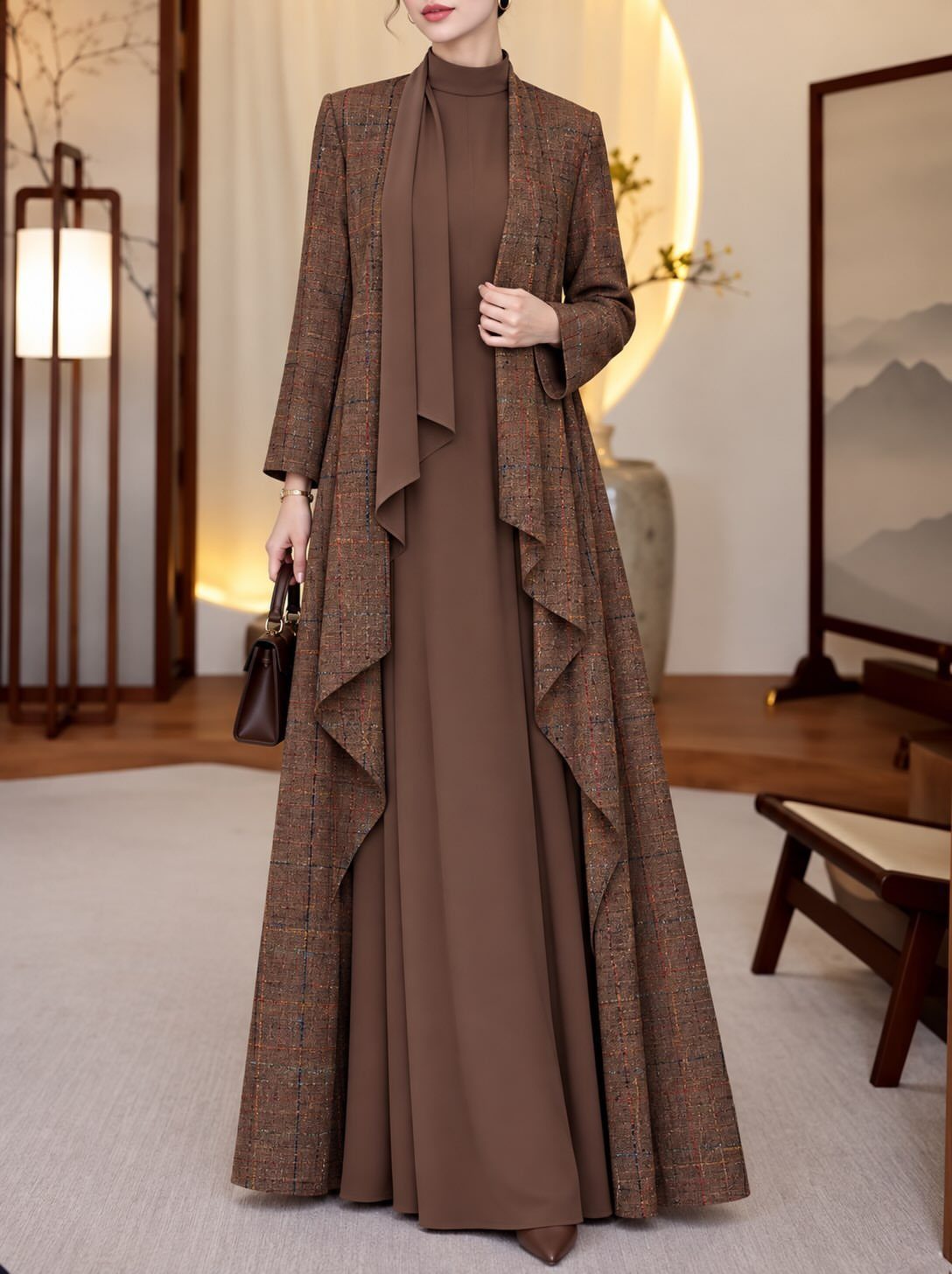 Woman wearing a long brown structured coat dress in a minimalist room.