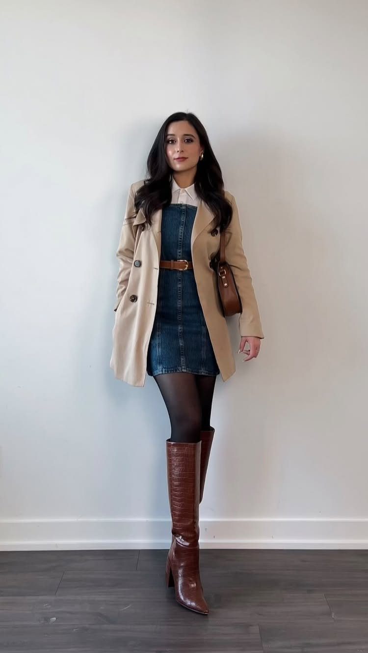 Woman wearing a tan trench coat, denim dress, and tall brown leather boots.